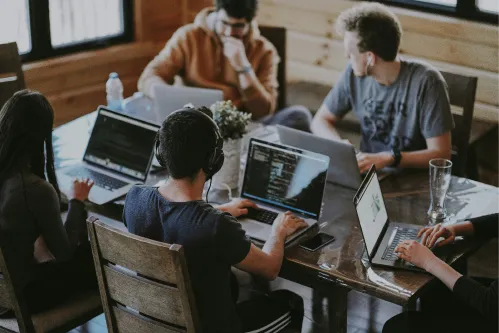 Image of team sitting at a table working on computers